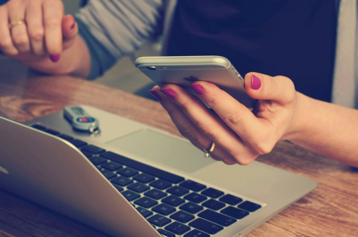 Person holding smartphone above laptop to make an online payment
