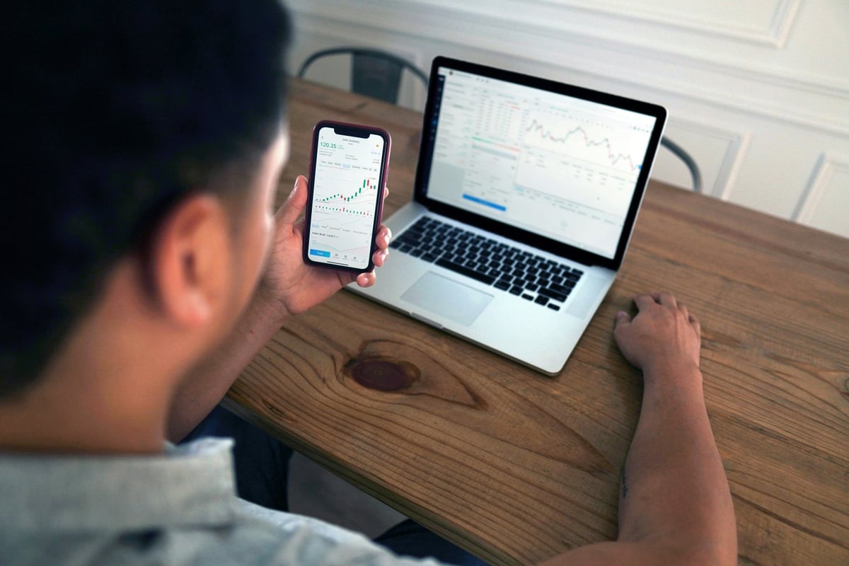 Person working on laptop and phone to manage online payments through a SaaS dashboard