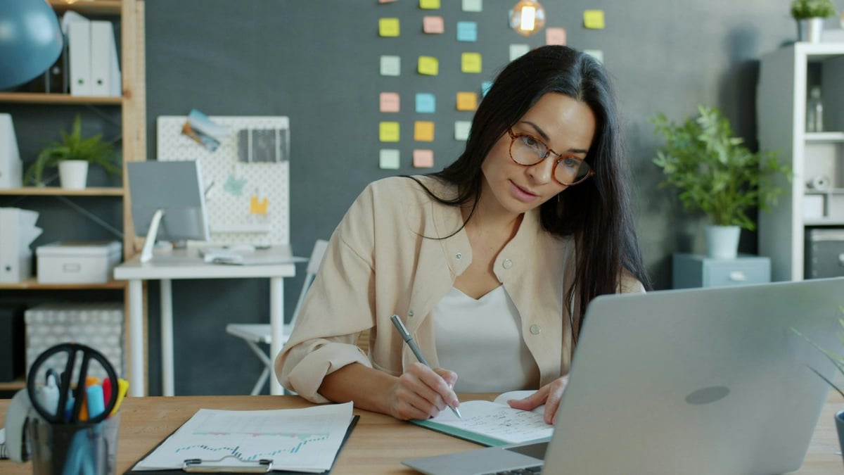 Tutor at desk with laptop planning lesson payments